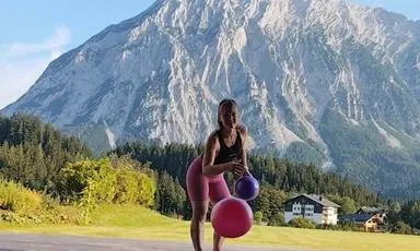 Pilates-Einheit auf der Matte im Bewegungsraum Hotel Hechl, Lisa wirft Pilatesbälle Richtung Kamera