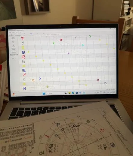 Ein Laptop mit einem Planetenauszug am Bildschirm und ein Horoskop Radex liegt davor.