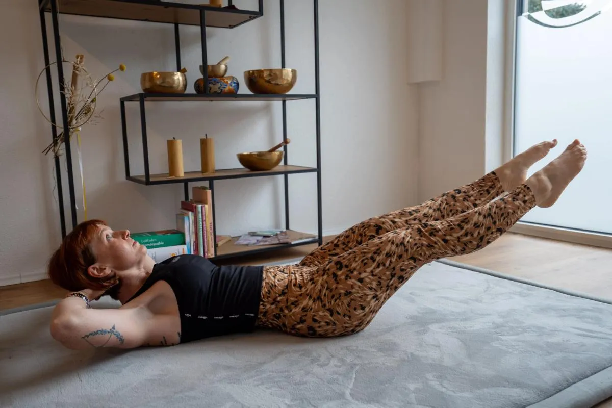 Dieses Foto zeigt Lisa auf der Matte in ihrer Praxis in einer Pilatesfigur